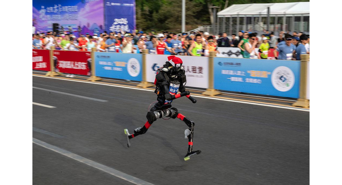 北京の公道マラソンイベントで人型ロボットが走行している様子。沿道には観客が並び、ロボットが競技に参加している場面。