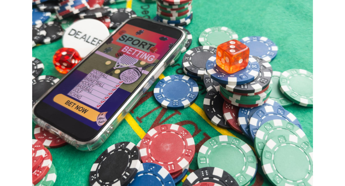 スマートフォンに表示されたスポーツベッティング画面の周りにカジノチップやサイコロが並び、オンライン賭博やデジタルベッティングを示すイメージ。