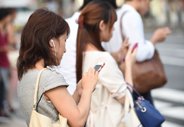 街中で複数の人がスマートフォンを操作している様子で、SNS利用やスマホ依存を表したイメージ画像