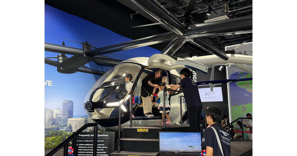 大阪・関西万博で展示された空飛ぶ車の実機を撮影した写真。来場者が機体内部を見学しており、次世代モビリティとして注目されるeVTOL（電動垂直離着陸機）の実用化に向けた取り組みを表している。SF映画で描かれた未来の乗り物が現実になりつつある様子を伝えている。