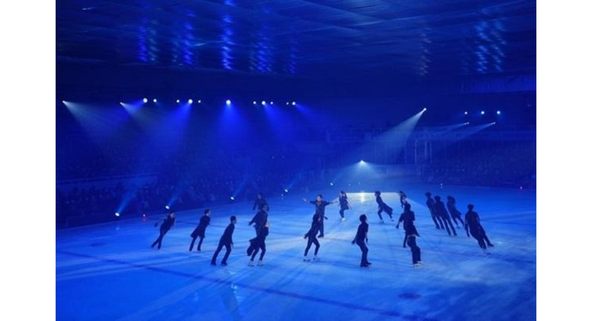 スポットライトに照らされたアイスリンクで複数のスケーターが演技する様子のイメージ